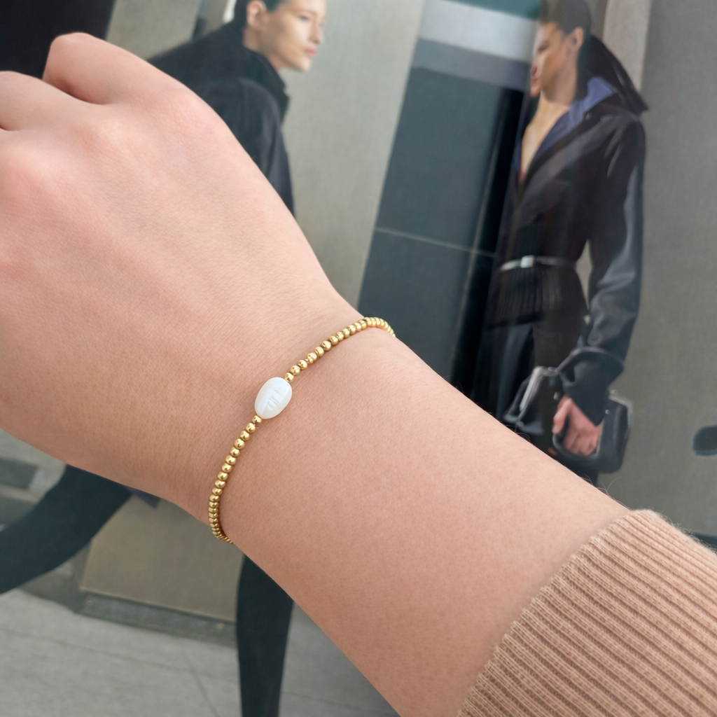 Single pearl stretch bracelet with 2mm gold beads on wrist – minimalist waterproof jewelry by XMTX Collections